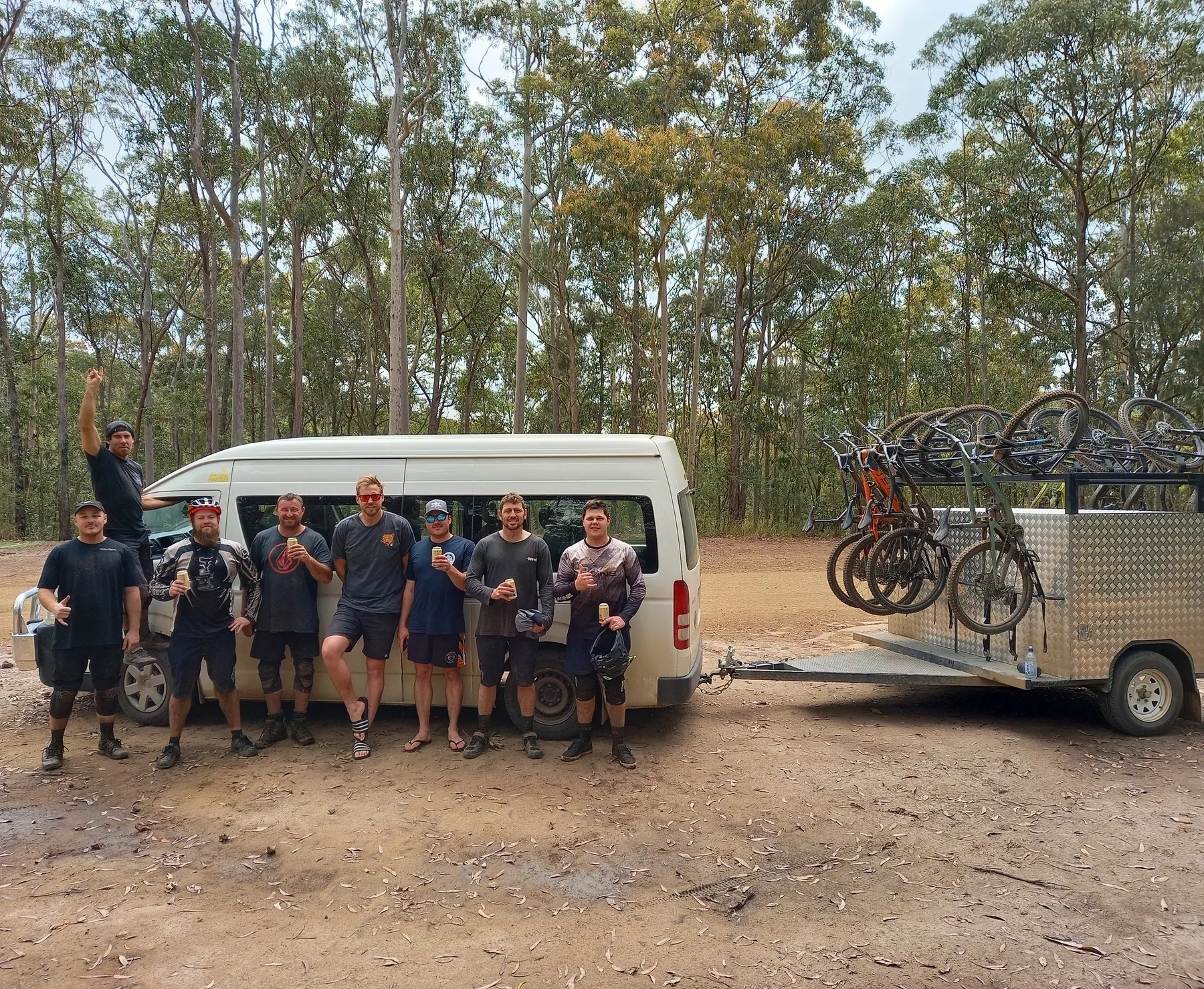 A group of riders in front of the Granted Ride bus and loaded trailer in the forest