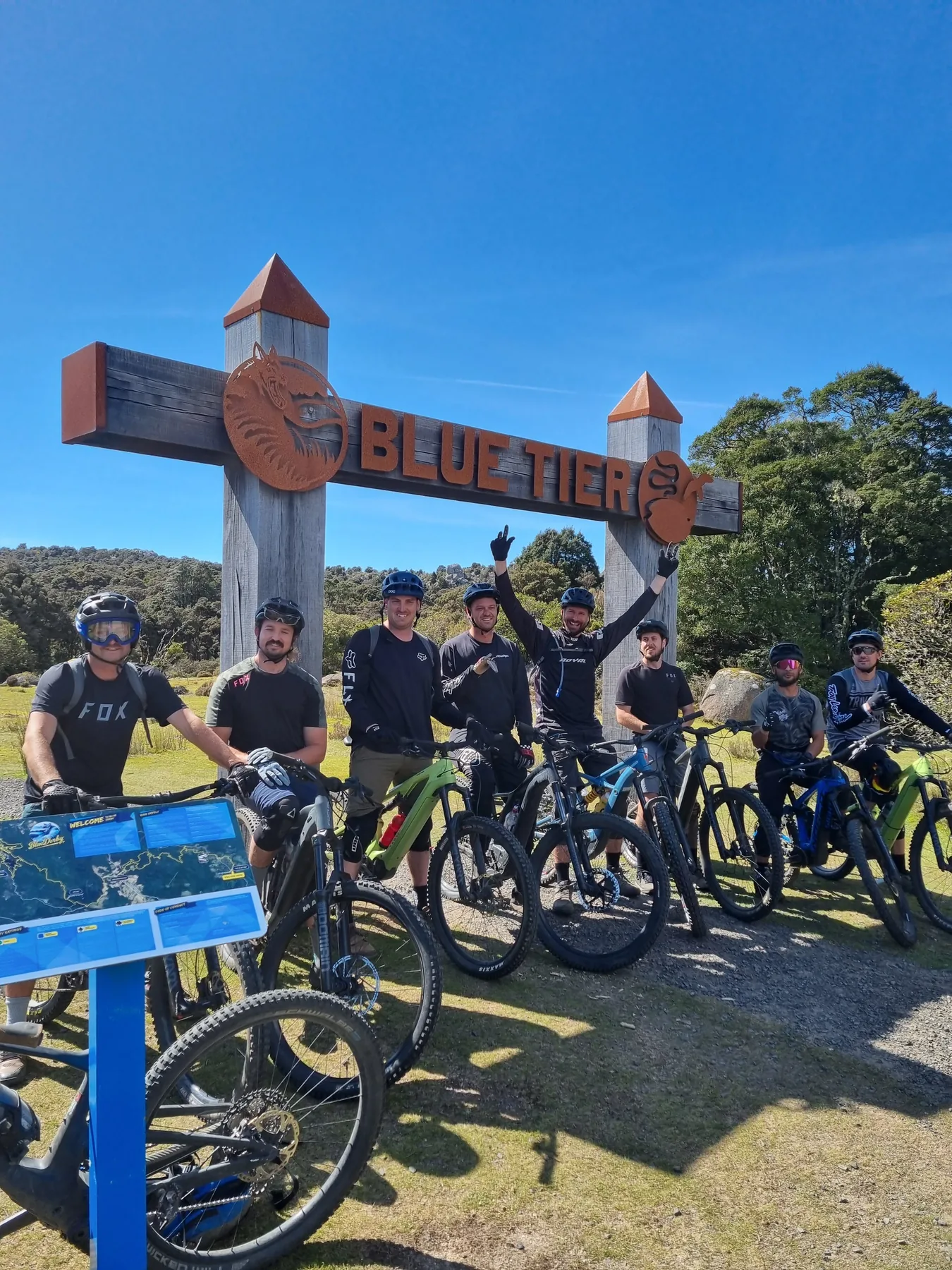 Riders under the Blue Tier trail sign in Tasmania