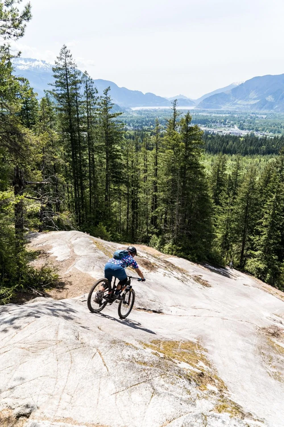 A rider on a granite slab above a valley in British Columbia